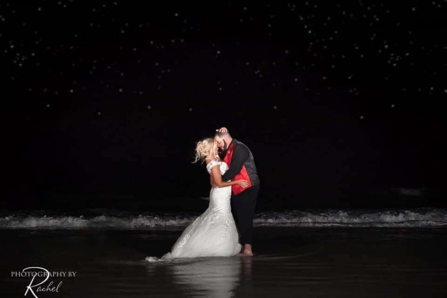 Bride and groom kissing in the ocean at night at Guy Harvey